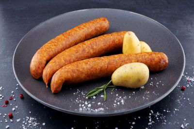 Kartoffelwürstchen serviert auf Teller mit ganzen Kartoffeln