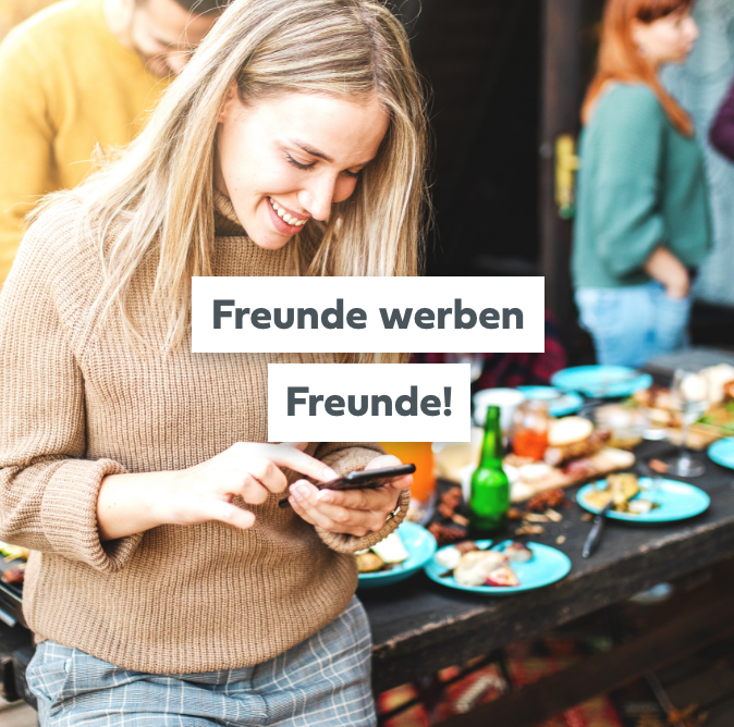 Das Bild zeigt im Hintergrund eine Feier mit Freunden und Familie, die gemeinsam gegrillt haben. Die Atmosphäre ist fröhlich und entspannt, mit Menschen, die lachen, essen und miteinander plaudern. Im Vordergrund des Bildes steht eine Frau, die ihr Handy in der Hand hält und darauf schaut. In der Mitte des Bildes steht der Text "Zu unserem Blog", der den Betrachter ermutigt, den Blog von MySchaschlik zu besuchen. 