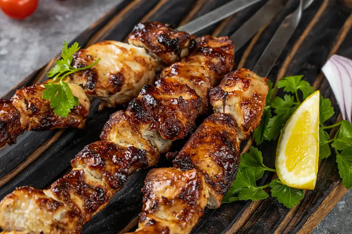 Nahaufnahme von Pute Schaschlik gegrillt auf einem Holzbrett angerichtet mit Petersilie, Zitrone und roter Zwiebel. Serviervorschlag.