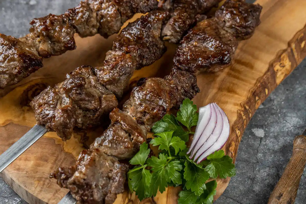 Lamm Schaschlik Original auf Spießen serviert auf Holzbrett