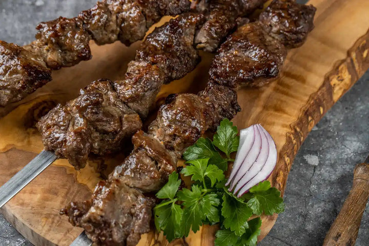 Lamm Schaschlik Original auf Spießen serviert auf Holzbrett