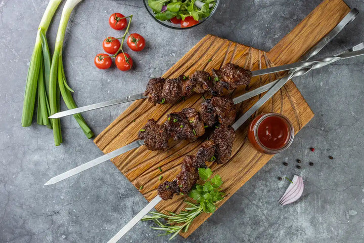 Draufsicht Rinder Schaschlik Barbecue auf Spießen serviert auf Holzbrett mit Petersilie und Barbecue Sauce