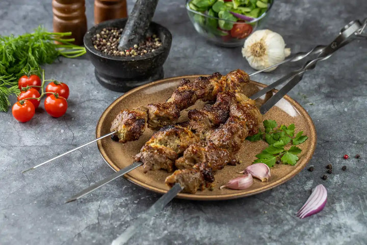 Schweine Schaschlik Knoblauch Pfeffer auf Spießen serviert auf Teller mit Knoblauch und Petersilie