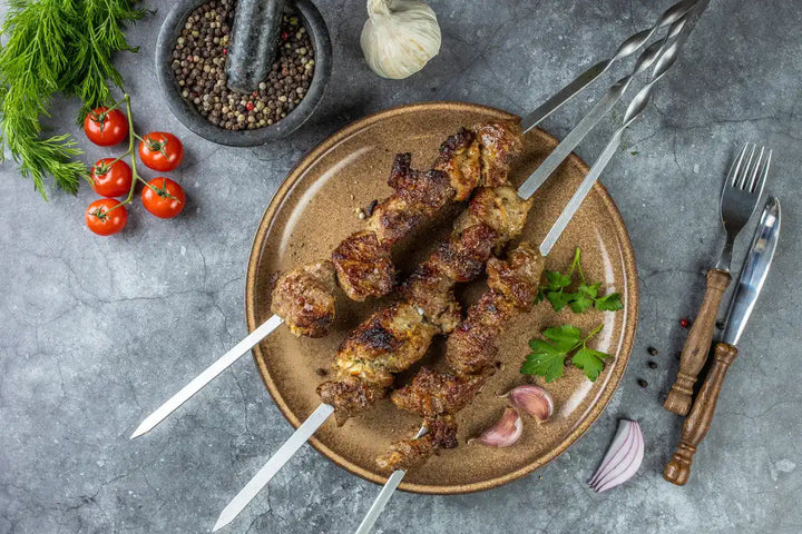 Draufsicht Schweine Schaschlik Knoblauch Pfeffer auf Spießen serviert auf Teller mit Knoblauch und Petersilie