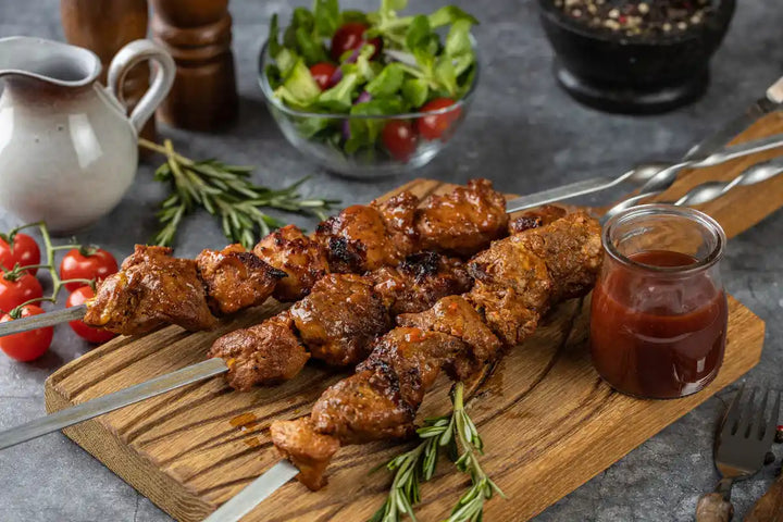 Schweine Schaschlik Barbecue auf Spießen serviert auf Holzbrett mit Barbecue Sauce