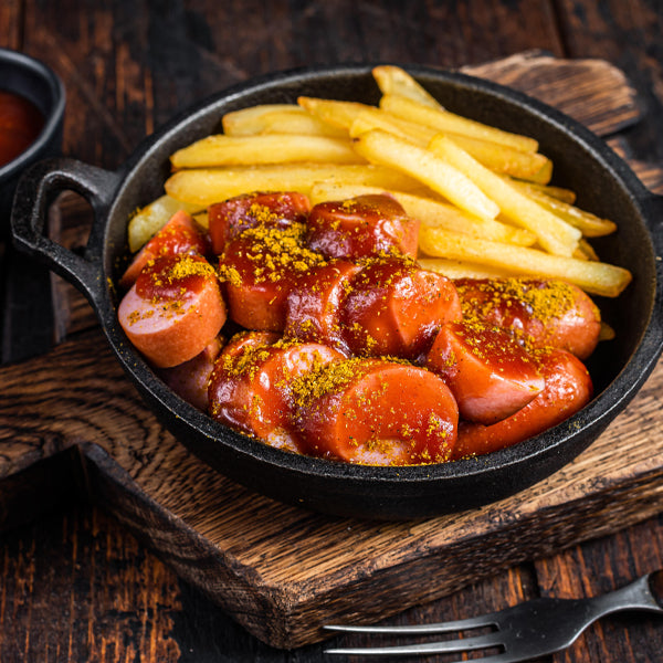 Currywurst in Pfanne mit Pommes serviert