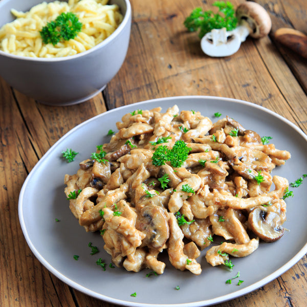 Putengeschnetzeltes mit Champignonsauce auf Teller serviert mit Spätzle