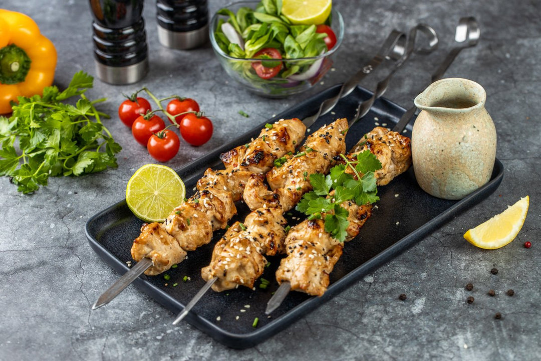 fertig gegrilltes Hähnchen-Schaschlik Teriyaki auf einer Platte dekoriert mit einer Limette und Petersilie